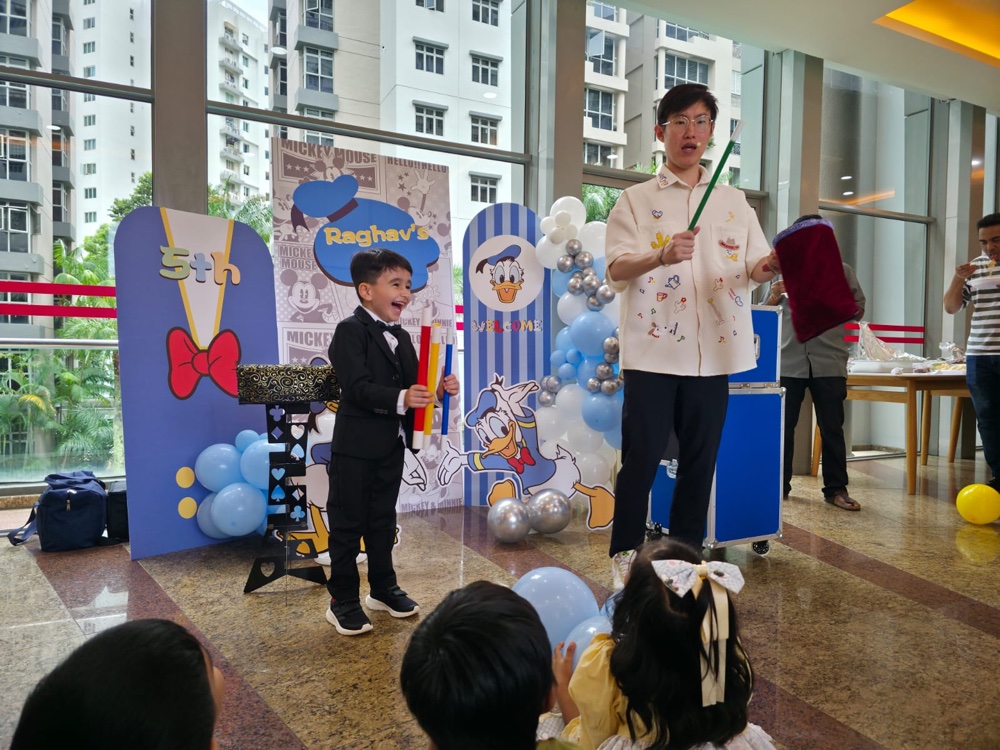 Birthday party magic show with excited child volunteer on stage